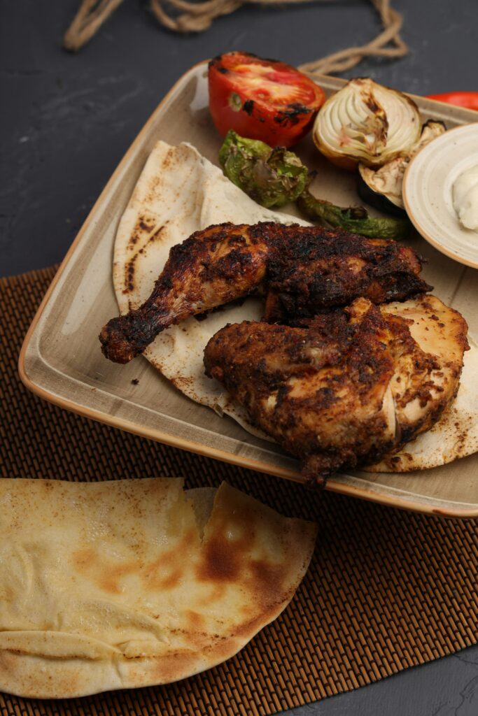 Double Leg Dinner with grilled chicken drumstick and thigh, served with pita bread, grilled tomato, onion, and dipping sauce