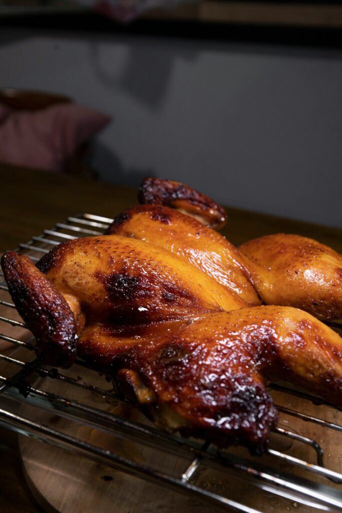 Golden roasted Half Chicken Dinner with crispy skin and juicy meat resting on a cooling rack after cooking.
