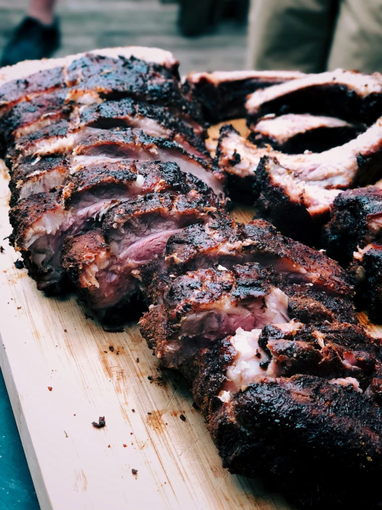 Close-up of juicy 1/3 Rack BBQ Ribs sliced on a wooden cutting board, featuring a smoky bark, tender meat, and caramelized barbecue crust.